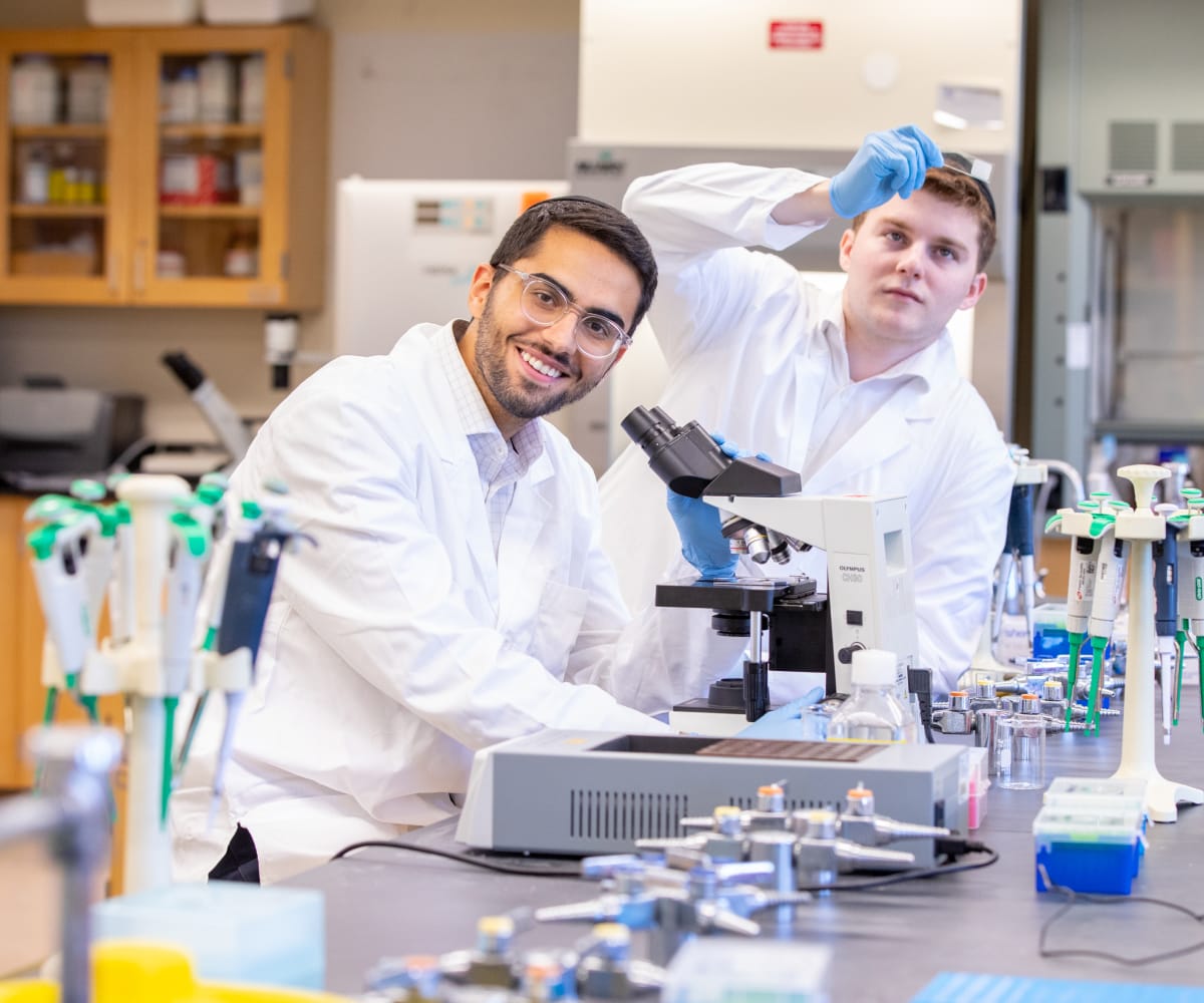 two students working on a microscope in science lab
