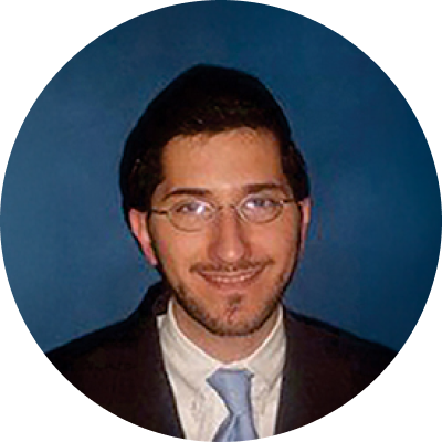 Amichai Avrahami smiling and wearing glasses, suit, and tie