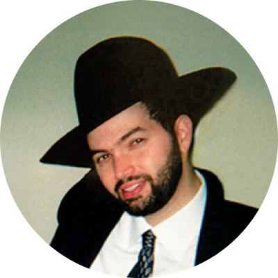 Chaim David smiling and wearing hat, suit, and tie