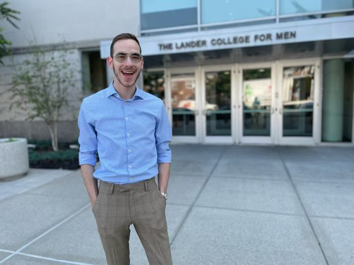 Avi Menaged, Student Government President, in light blue button down shirt and khaki pants, standing with hands in pant pockets in front of Lander College for Men building.