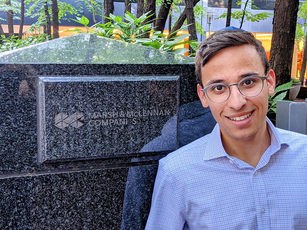 Yitzchak Lisker standing in front of Marsh McLennan Companies sign