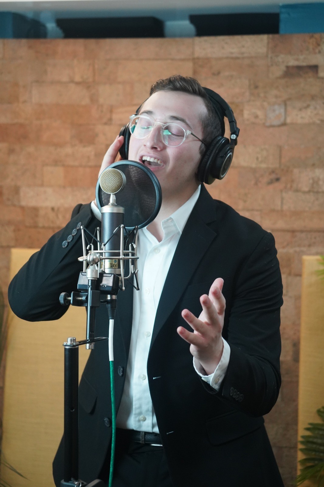 Dovid Pearlman singing into a mic, with headphones, while recording his album