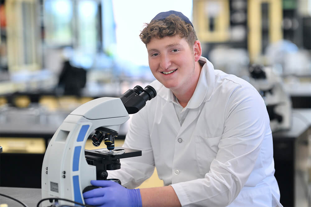 Adam Commer in science lab with microscope at LAS in Flatbush