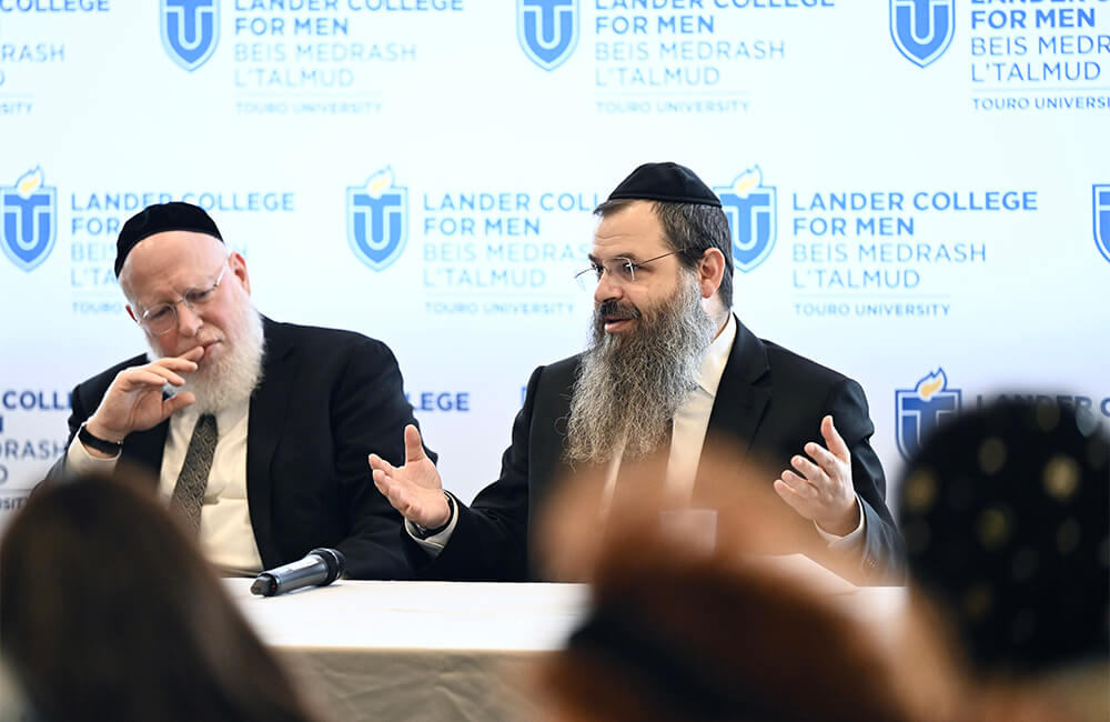 Rosh HaYeshiva Rabbi Yonasan Sacks and Menahel Rabbi Yosef Sonnenschein sit at a table answering questions from their audience