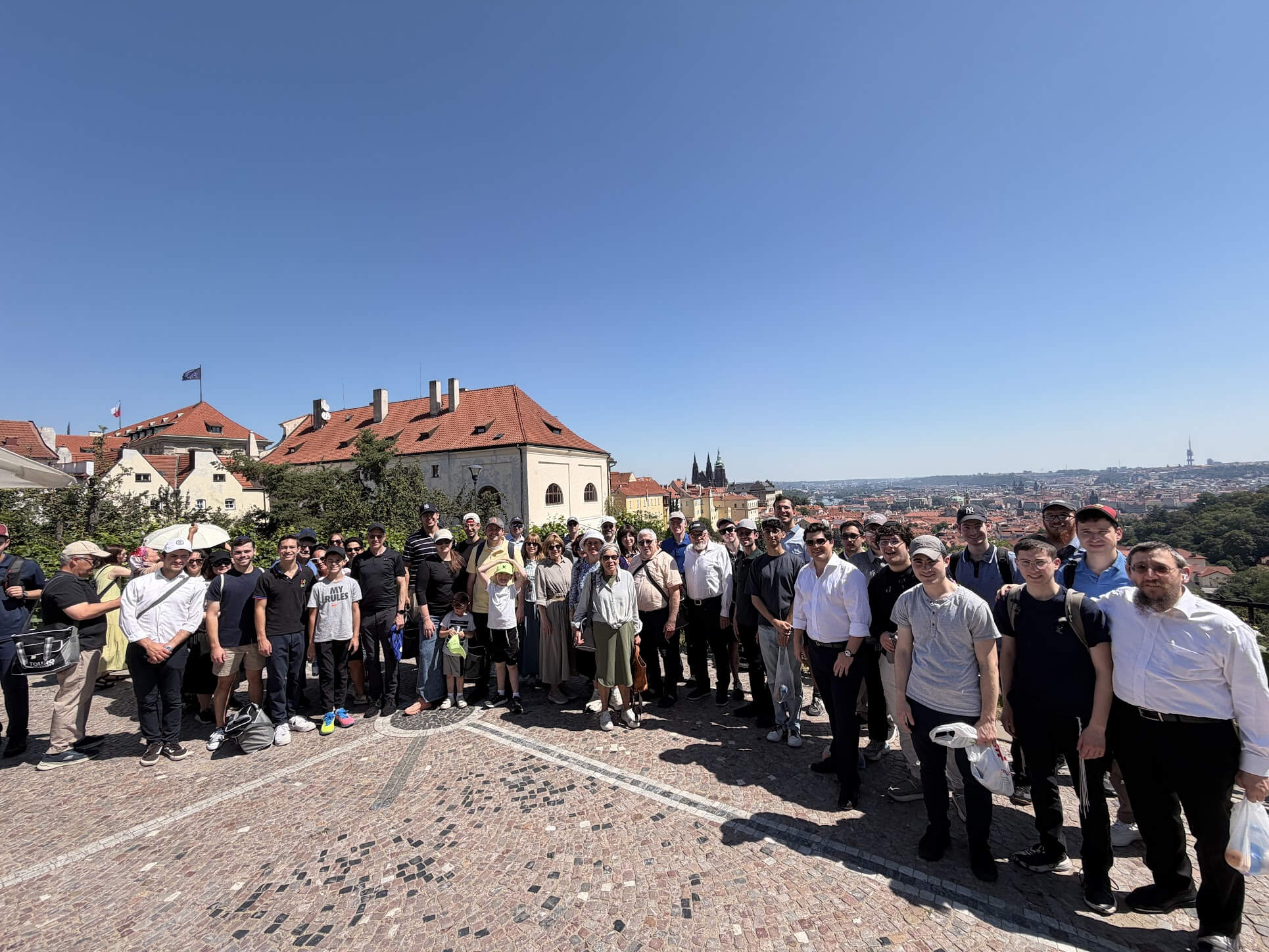 Group of men, women and children standing in front of a background of Prague