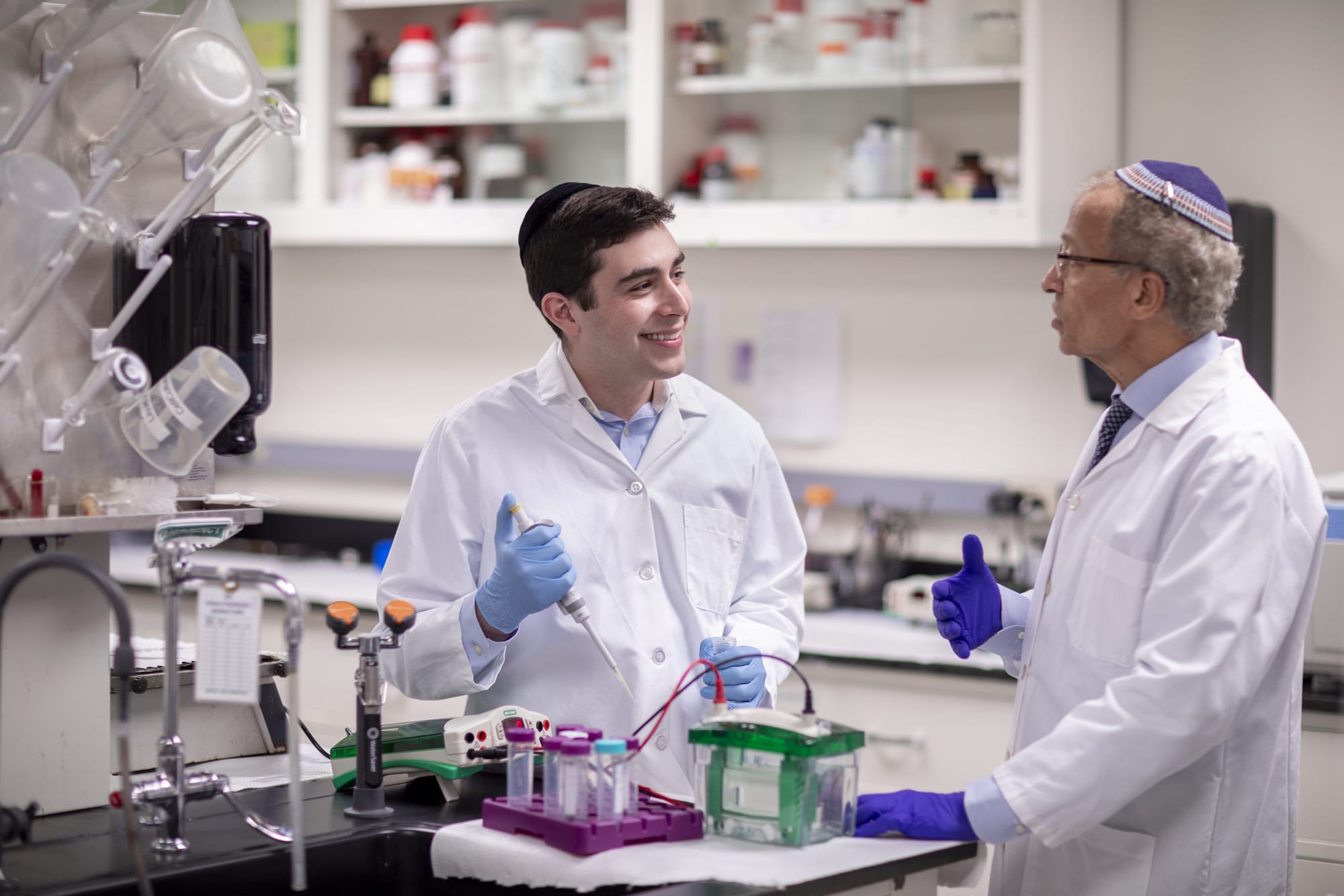 Yosef Buchen is talking to a professor in a lab classroom